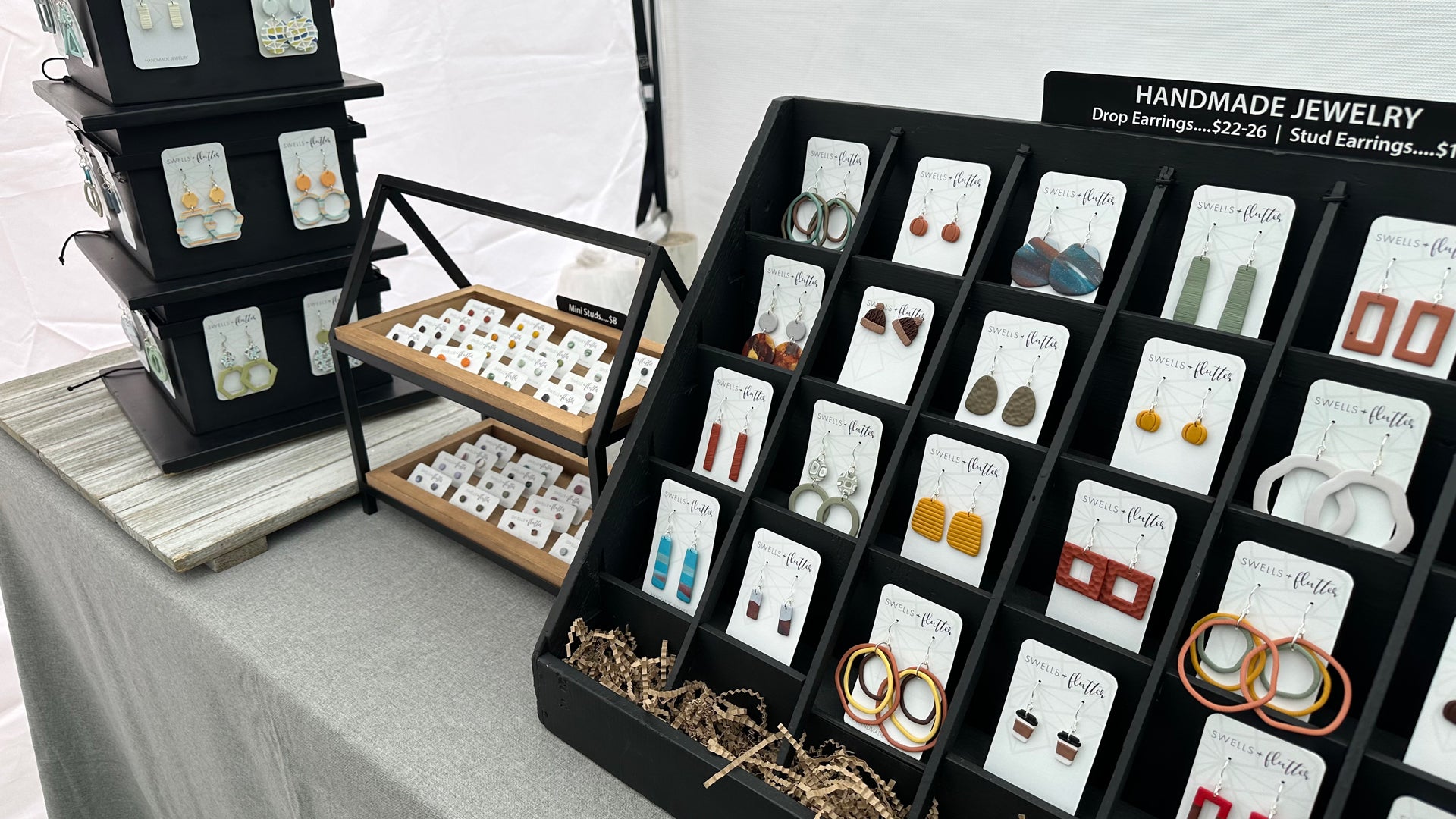 Handmade polymer clay earrings displayed on a table at an art market event.