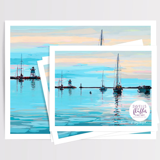 A stack of art prints showing a painted Grand Marais, MN harbor scene with sailboats, a lighthouse, and calm blue water under a pastel sky. A circular logo in the lower right reads 'Swells + Flutter Fine Art'. Artwork by Kristen Kozelouzek.
