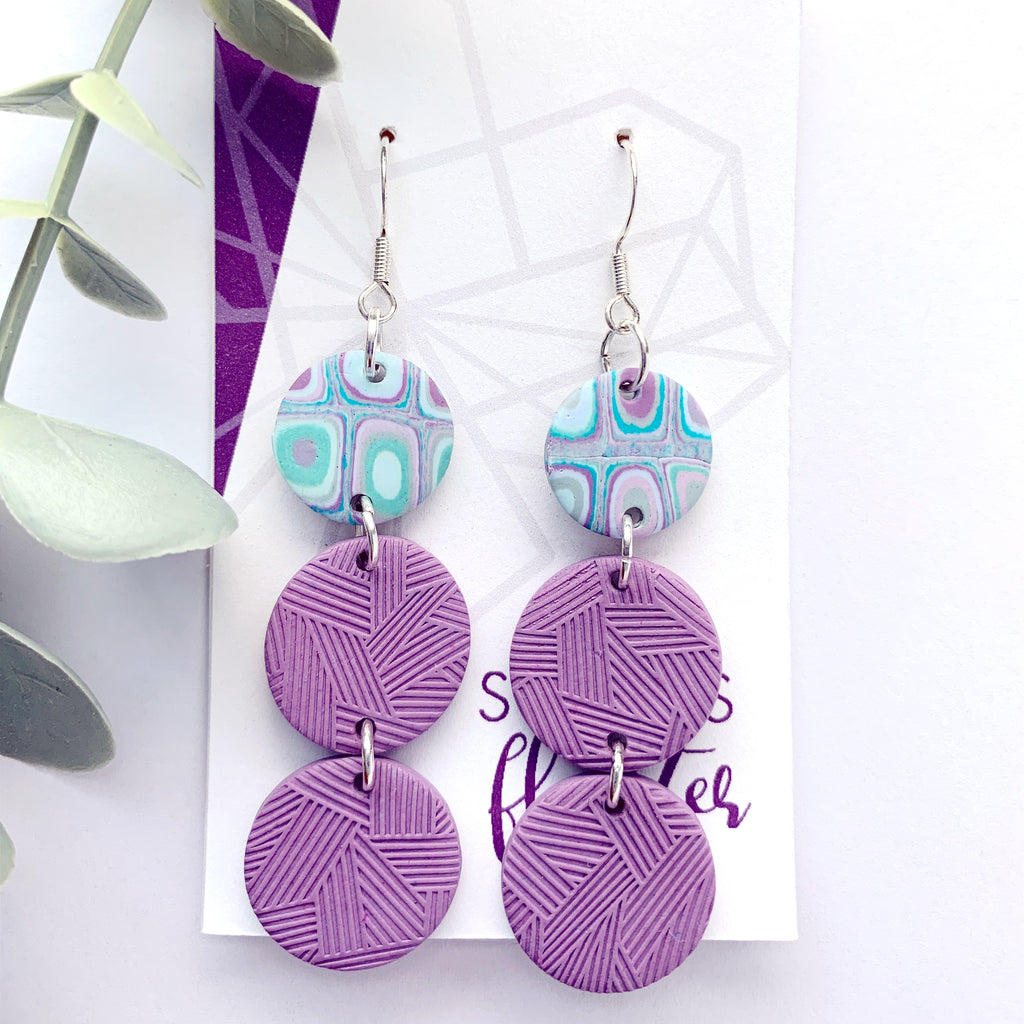 Three tiered circle drop earrings with two textured in purple and one teal/purple cane.